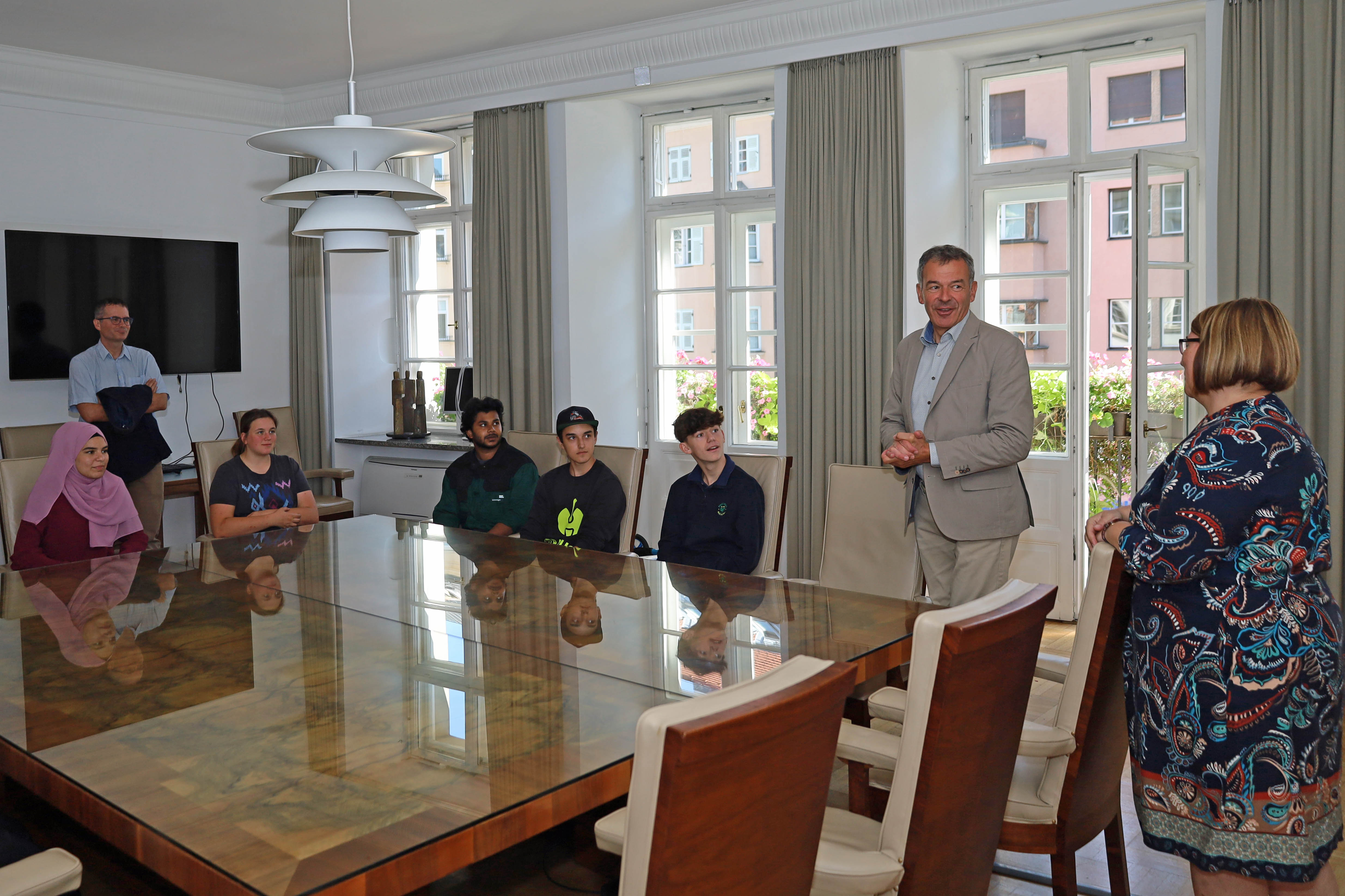 Innsbrucks Bürgermeister Georg Willi (l.), Amtsvorstand Wolfgang Hödl (Personalwesen, r.) und die städtische Lehrlingsbeauftragte Sabine Floßmann (5.v.l.) begrüßen die neuen Lehrlinge der Stadt Innsbruck im Stadtsenats-Sitzungszimmer im Rathaus.